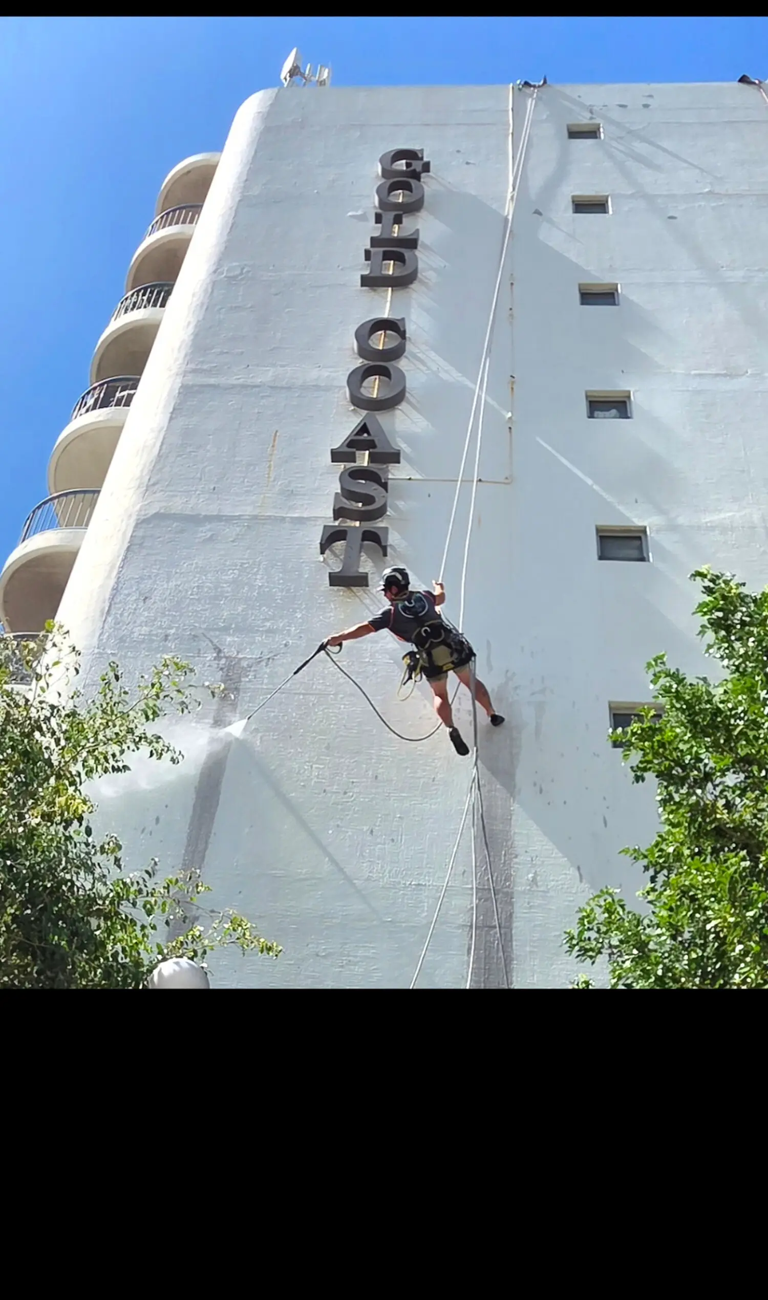 Rope access technicians working on a Gold Coast tower at dusk